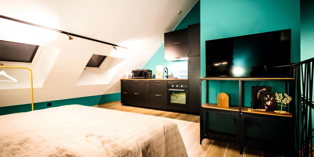 Espace suite privative avec lit douillet, kitchenette équipée, et décoration contemporaine